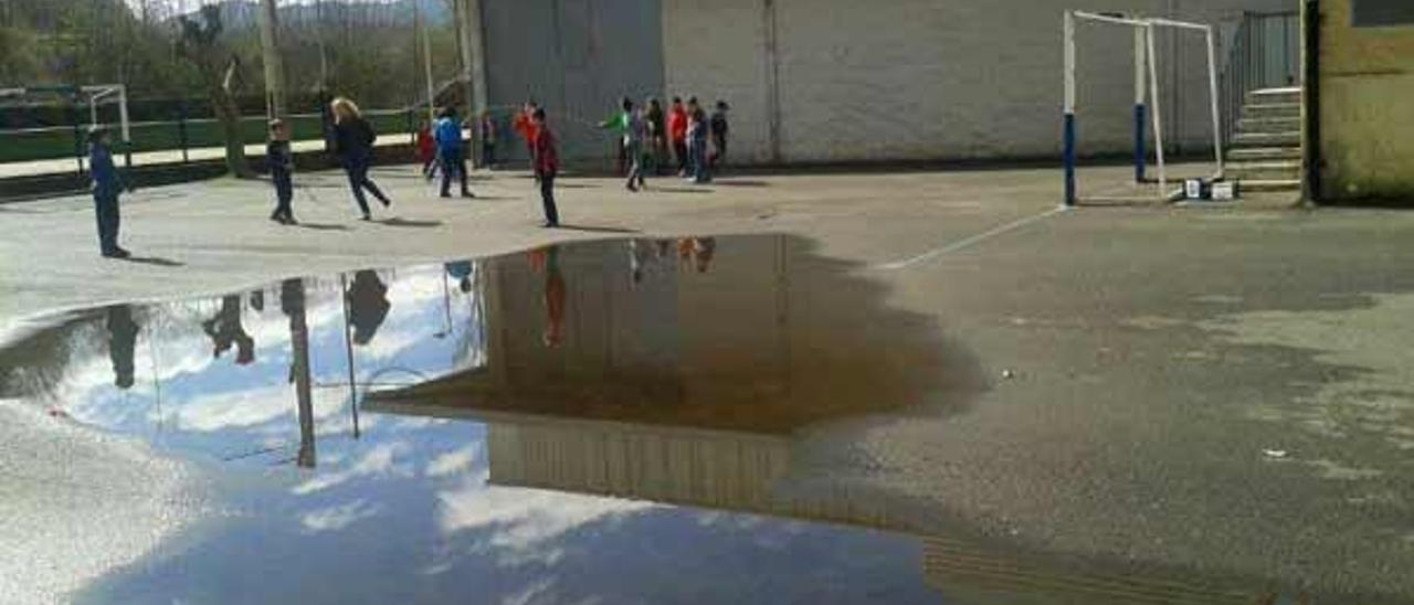 Alumnos del colegio público Río Sella, durante el recreo de ayer, con charcos en el patio.