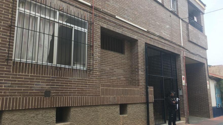 Un agente escolta la puerta del edificio donde se ha producido el incendio.