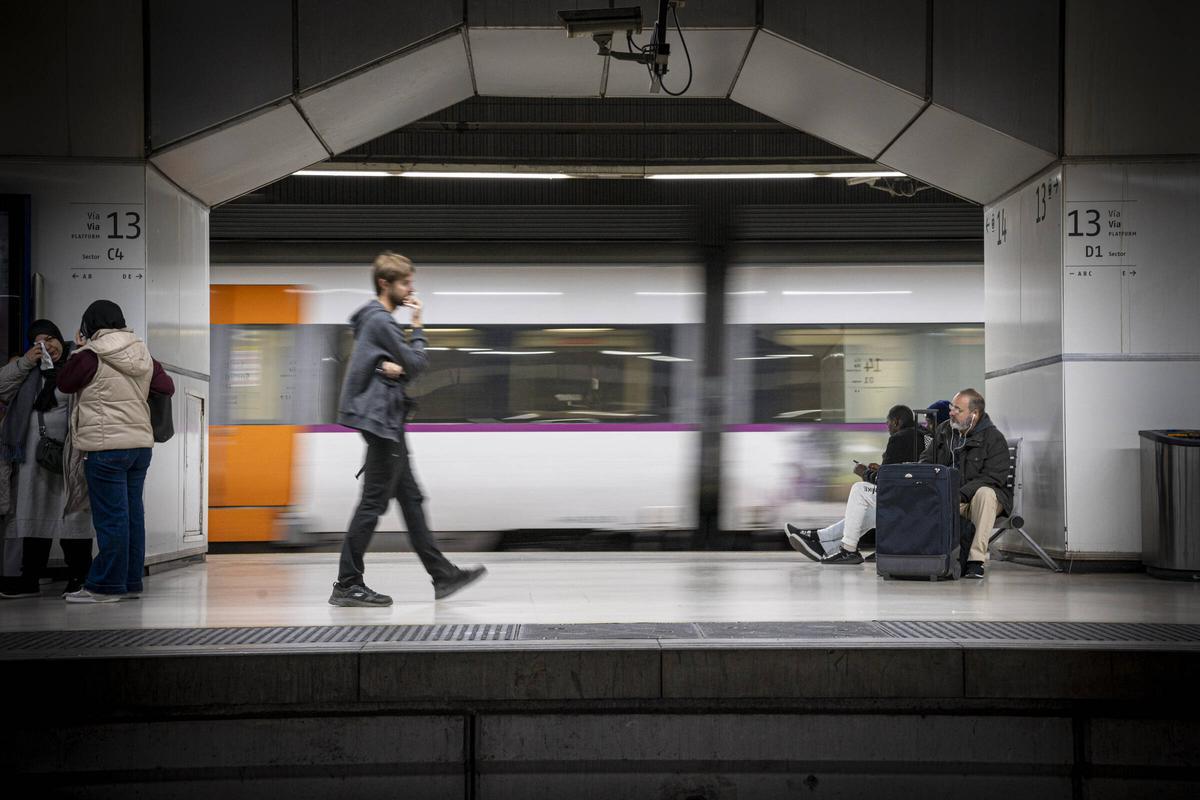 Varias personas esperan sus trenes en la estación de Rodalies de Sants, en Barcelona.