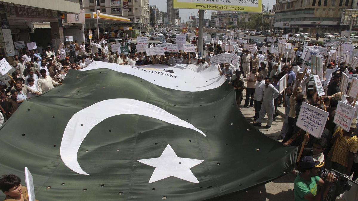Varias personas sostienen una bandera de Pakistán.