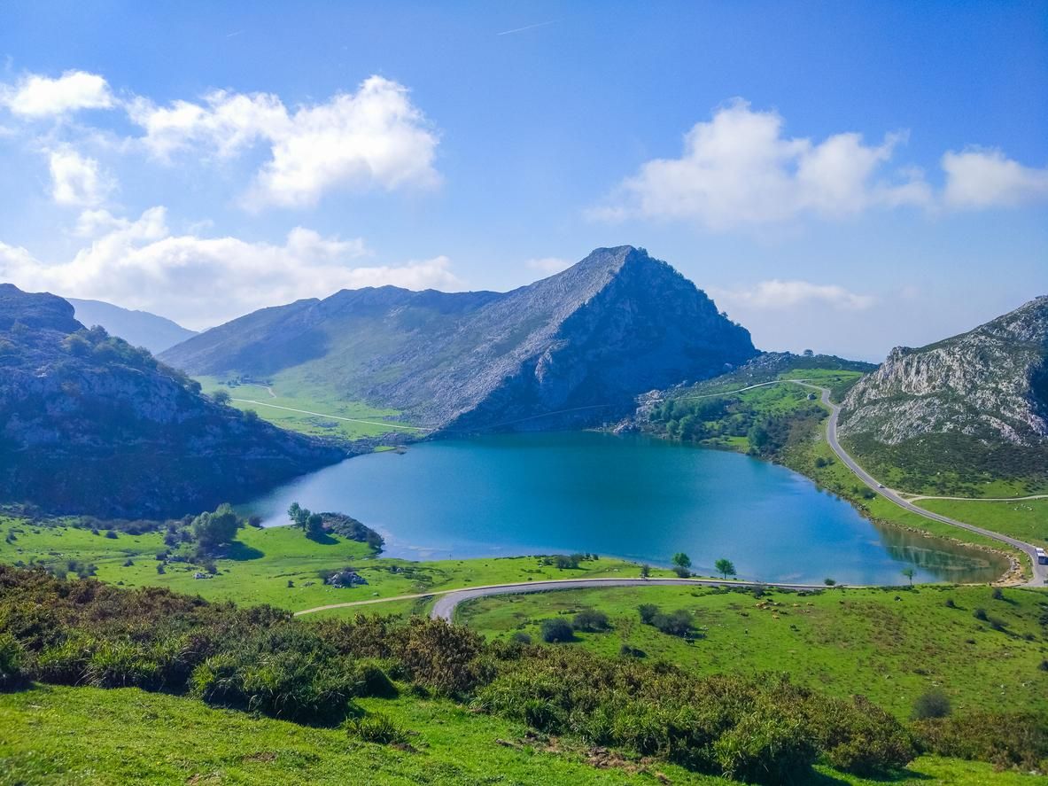 Vista del lago Enol en los lagos de Covadonga, Asturias, España, desde el mirador. Praderas verdes con montañas al fondo