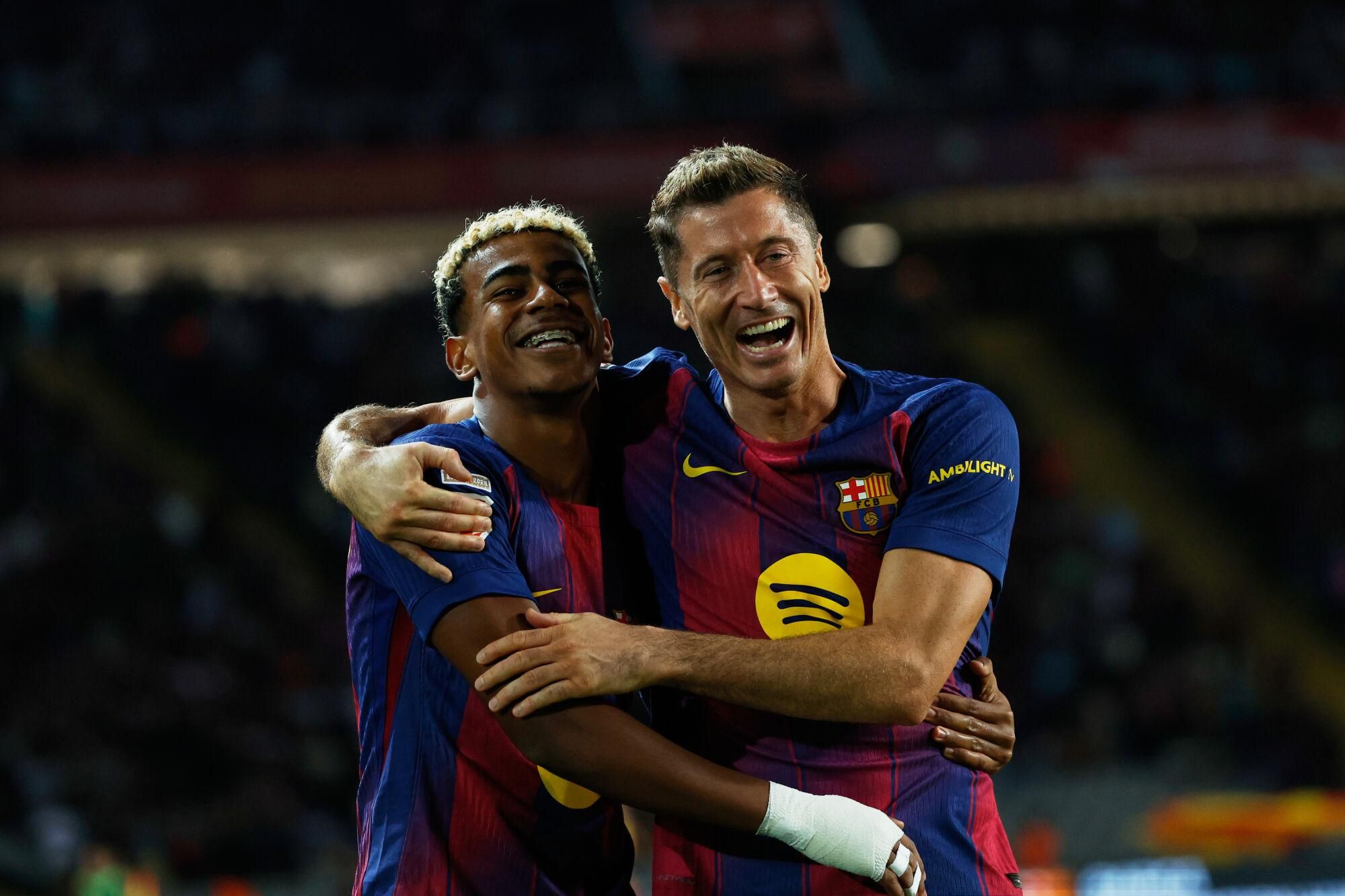 Barcelona's Robert Lewandowski, right, celebrates with Lamine Yamal scoring his side's first goal during a Spanish La Liga soccer match between FC Barcelona and Real Sociedad at the Lluis Companys Olympic Stadium in Barcelona, Spain, Sunday, Sept. 28, 2025. (AP Photo/Joan Monfort)