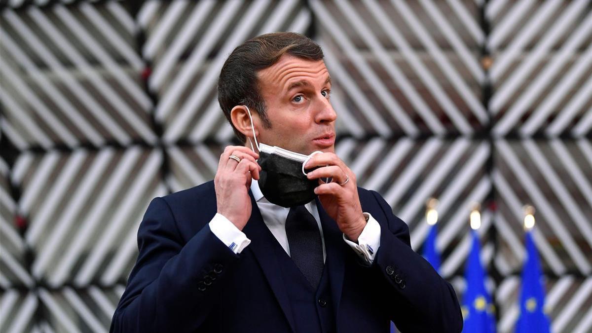 (FILES) In this file photo taken on December 10  2020 France s President Emmanuel Macron takes off his mask before speaking to the press as he arrives at the EU headquarters  Europa building in Brussels  prior to a European Union summit  - Macron tests positive for Covid-19   the presidency announced on December 17  2020  (Photo by JOHN THYS   POOL   AFP)