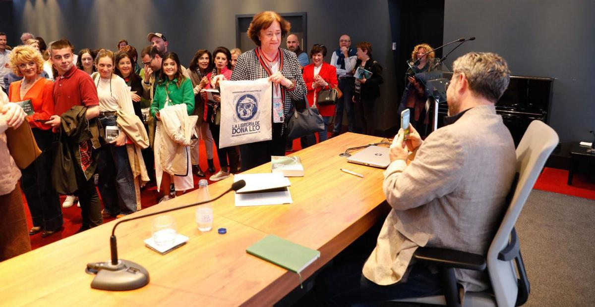 Máximo Huerta, durante la firma de libros, fotografía a una lectora con la bolsa de su tienda en Buñol, La Librería de Doña Leo. A la izquierda, el autor, con la escritora Mayte Uceda, afincada en Cudillero y con la que comparte agente editorial en Planeta. | Fernando Rodríguez