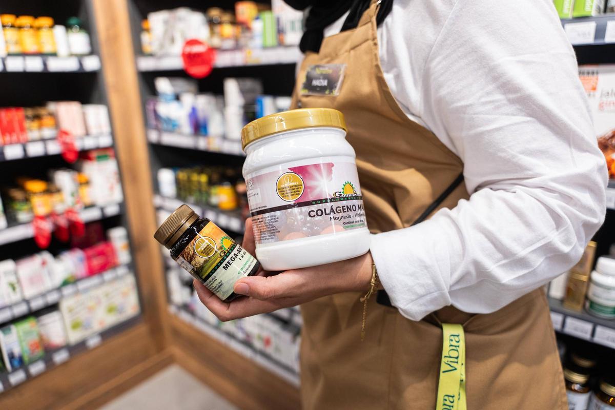 La dependienta de una herboristería de Barcelona sostiene envases de complementos alimenticios.