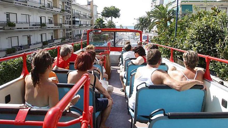 Turistas en la planta superior del autobús panorámico, que baja por una calle de La Cala de Benidorm hacia la playa de Poniente.