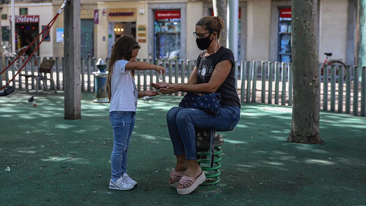 Una niña echa gel hidroalcohólico en las manos de su madre, en un parque de Barcelona, el pasado 6 de octubre