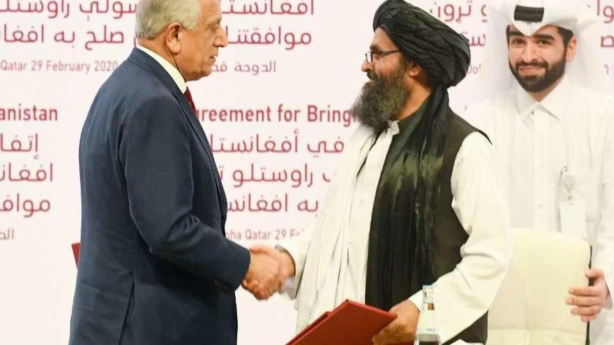 Baradar, líder de la delegación talibán (derecha), y Khalilzad, enviado por Estados Unidos, se dan la mano en la reunión de Doha. //Reuters