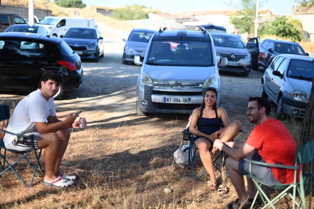 Tres jóvenes esperan a la sombre el eclipse en Juslibol.