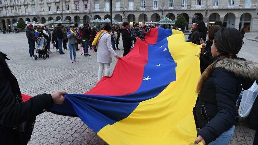 Un grupo de venezolanos extiende la bandera de su país en la plaza de María Pita.