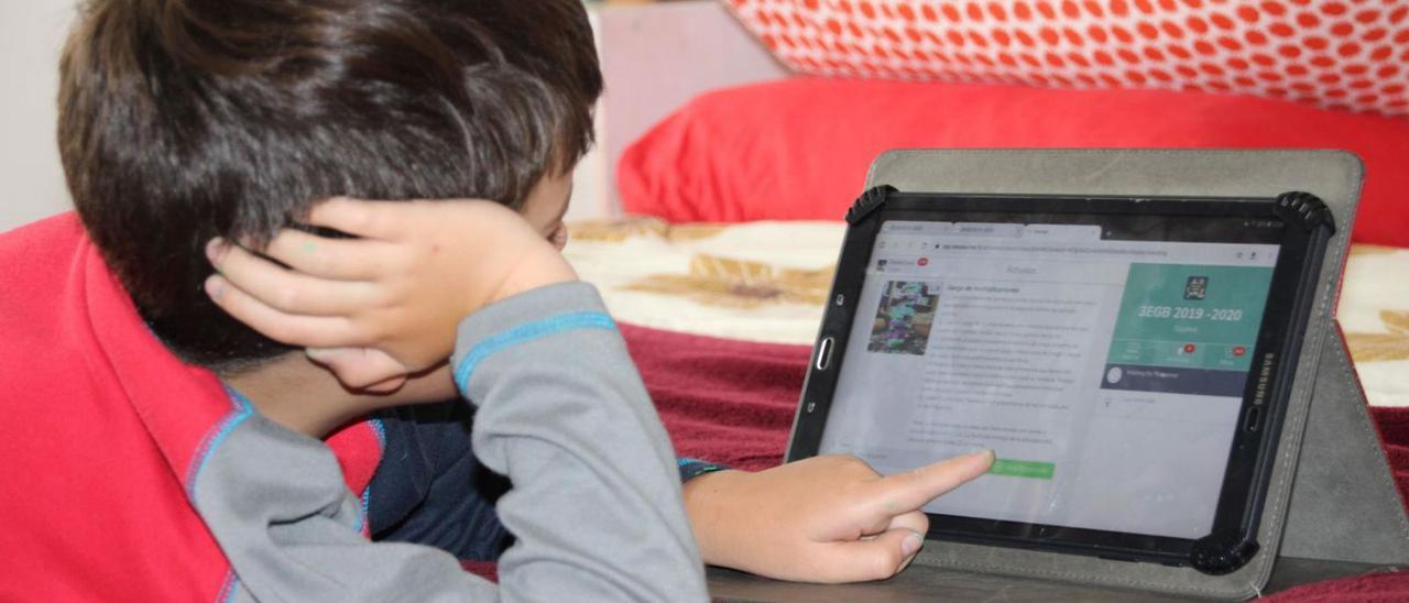 Un niño consulta la tablet en su casa. / EFE