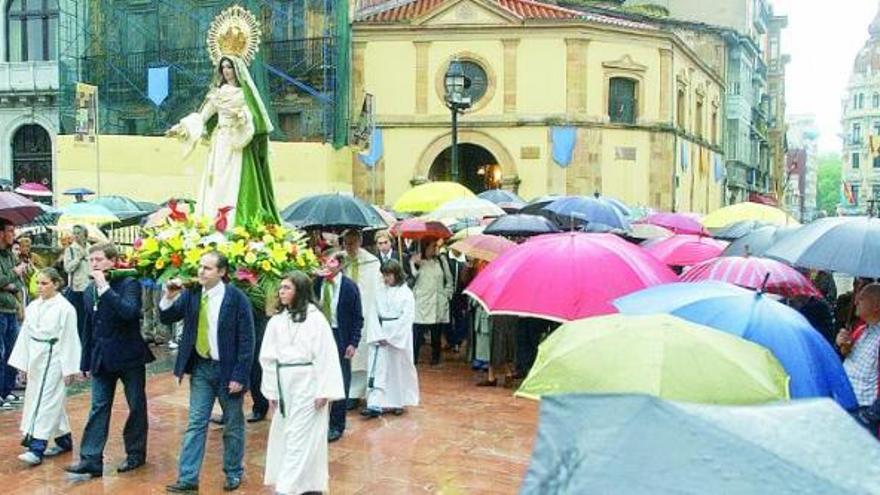 Cofrades y socios de La Balesquida conducen a la Virgen bajo la lluvia y en procesión hasta San Tirso.