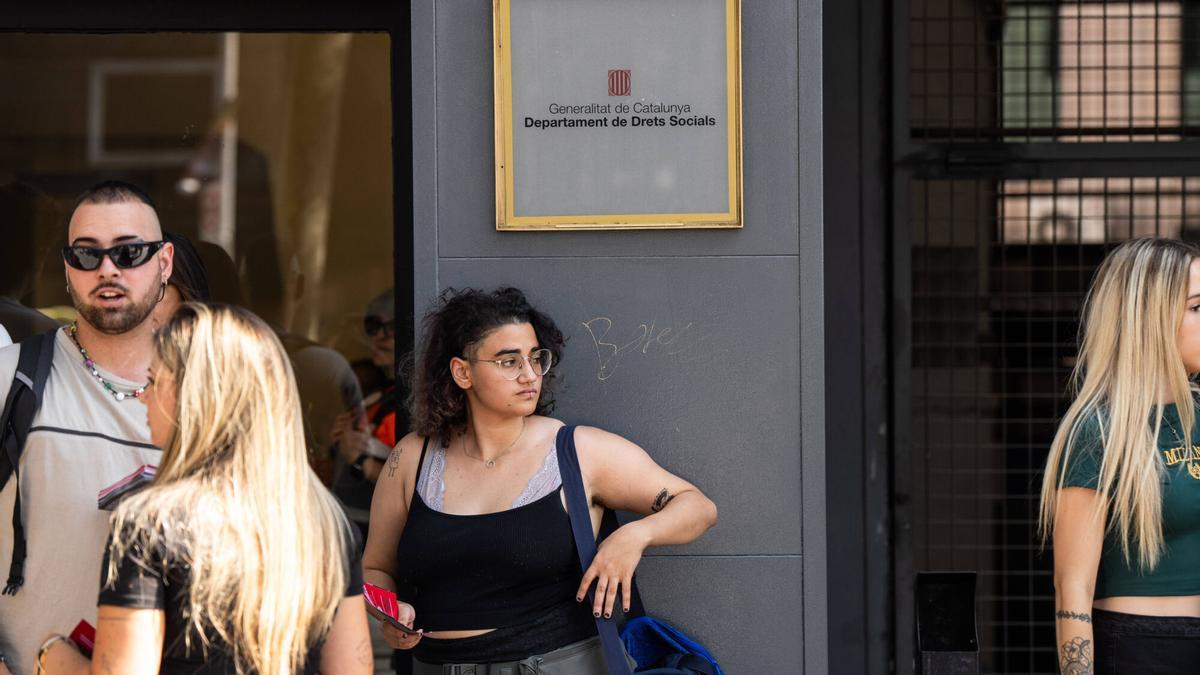 Una joven, bajo un cartel del Departament de Drets Socials