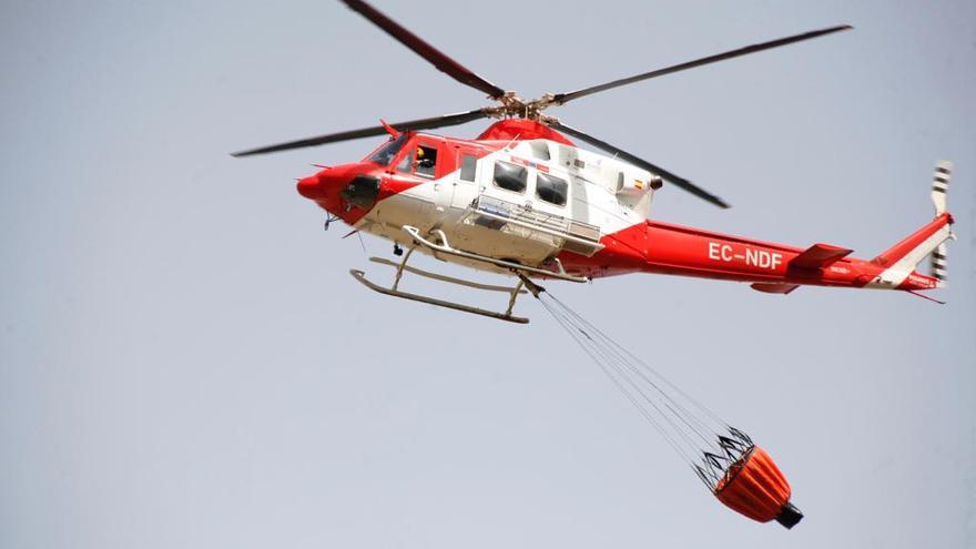 Uno de los helicópteros que trabaja en las labores de extinción recoge agua para apagar el incendio de Arico.