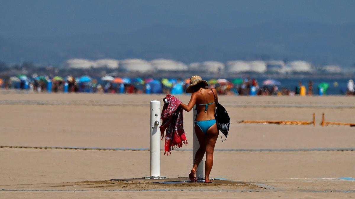 Una mujer se lava los pies en la playa de la Malva-rosa.