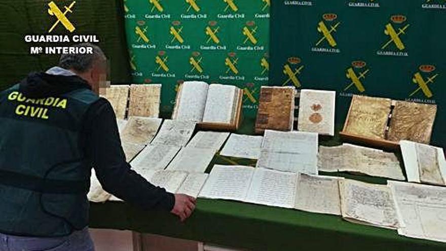 Un agente revisa los libros y legajos documentales recuperados por la Guardia CIvil de Murcia.