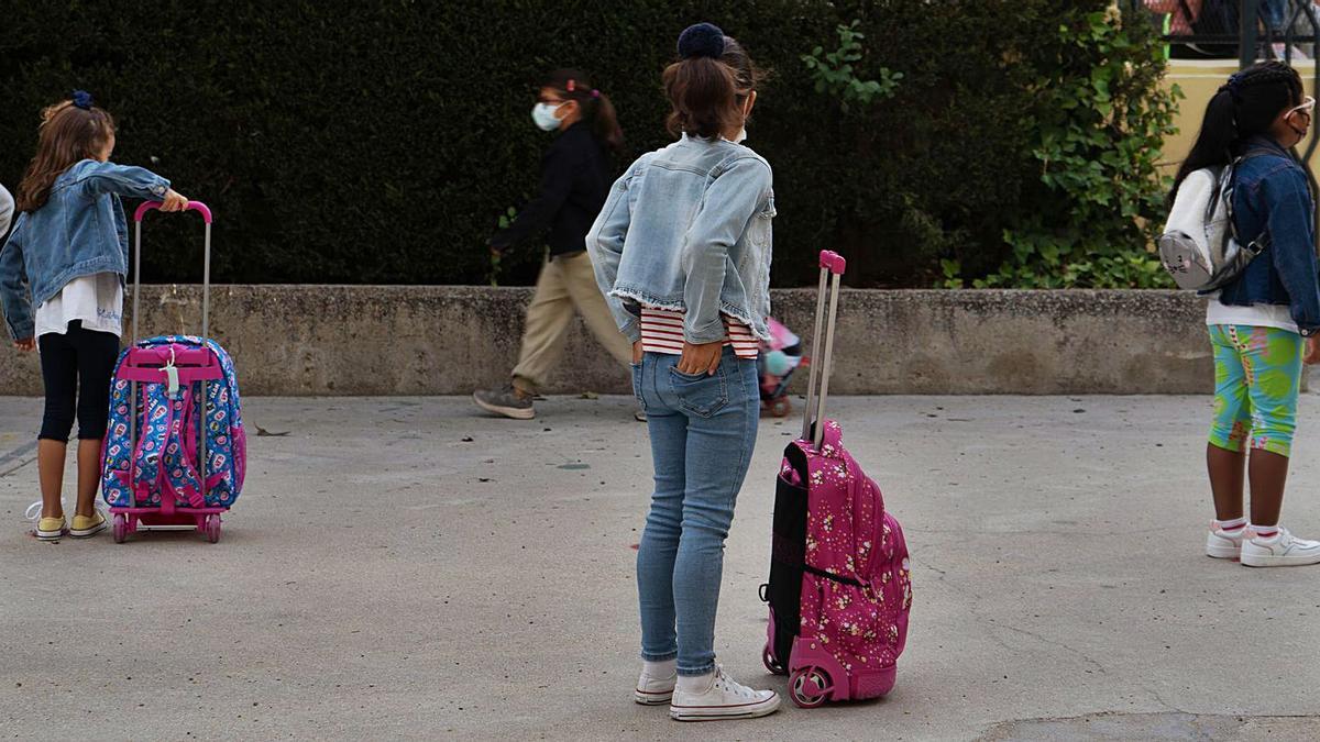 Los pequeños alumnos esperan ordenadamente y con distancia junto a sus mochilas a la apertura de las puertas del colegio. | Jose Luis Fernández