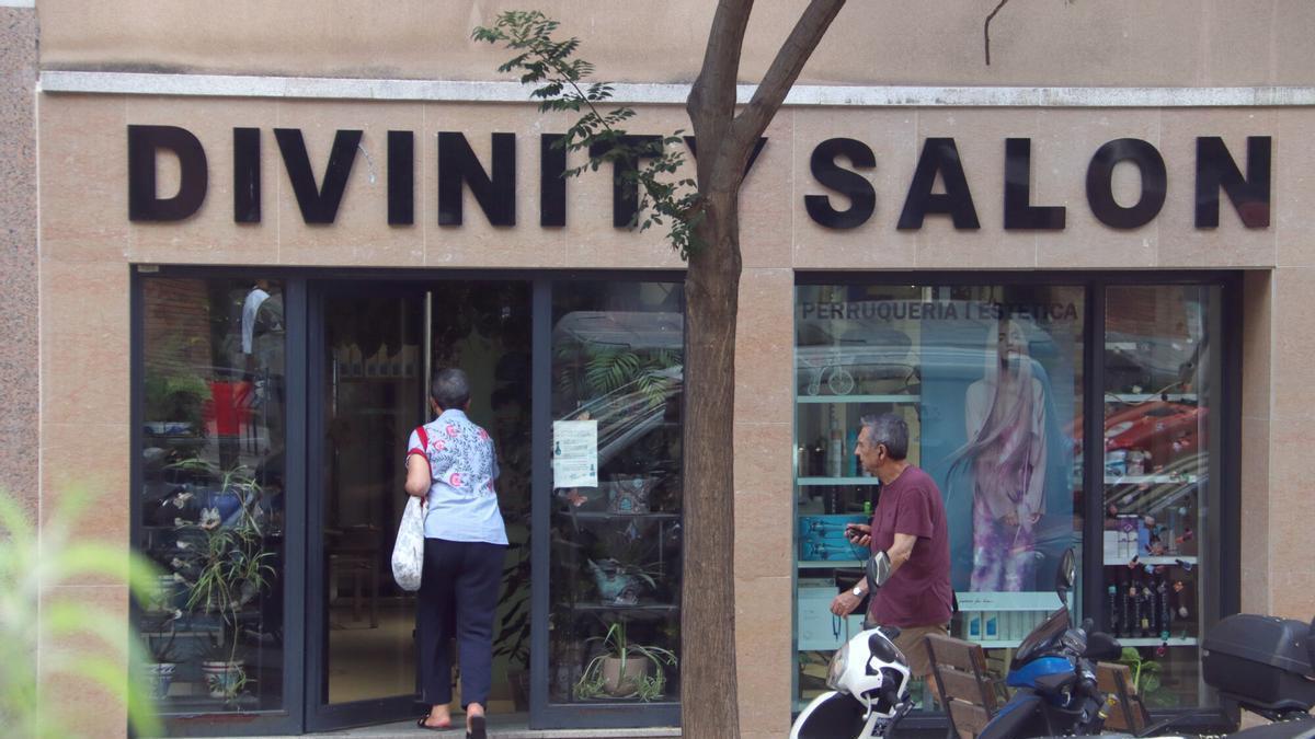 Una clienta entra en un centre d'estètica retolat en anglès, al districte de Gràcia