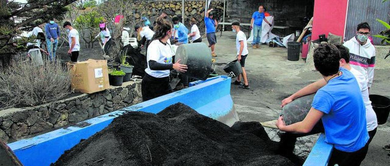 Imagen de los jóvenes y menores de este colectivo limpiando restos de ceniza. | | LP/DLP