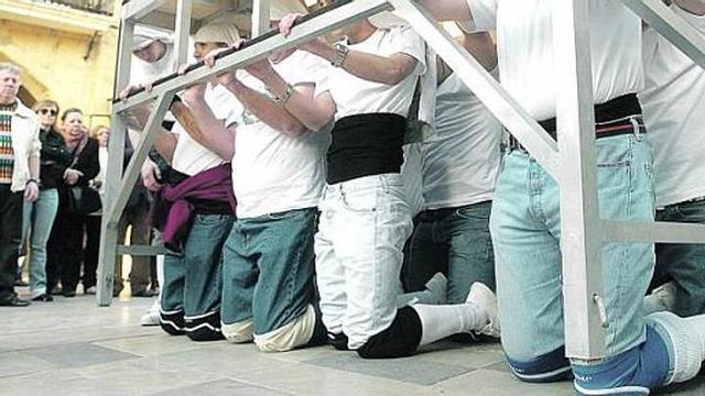 Ante el Ayuntamiento, los costaleros, de rodillas, ensayaron la compleja operación que tendrán que hacer para pasar bajo el arco del tránsito de Santa Bárbara.