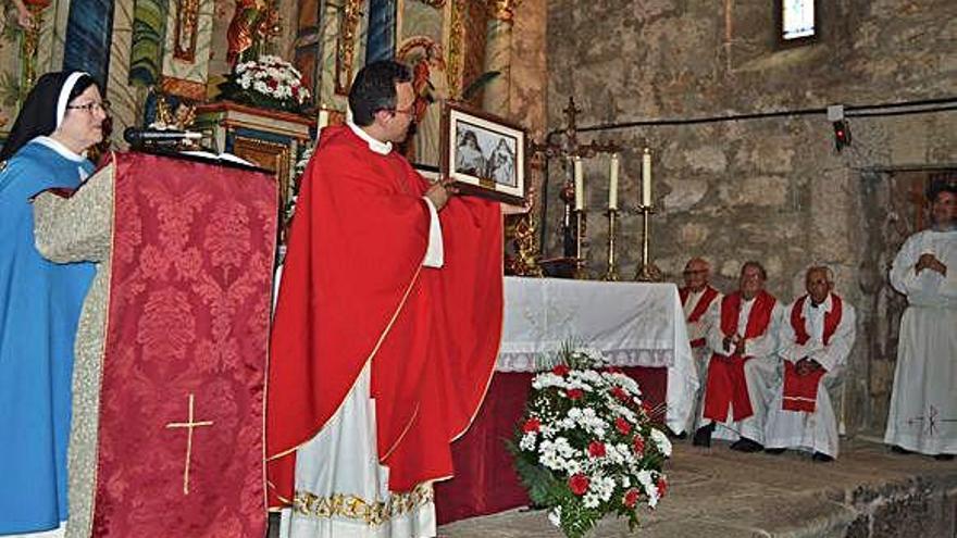 El párroco Fernando García muestra el cuadro de las mártires regalado por las Concepcionistas, junto a familiares en el centro. A la derecha, asistentes en el beso de la reliquia .