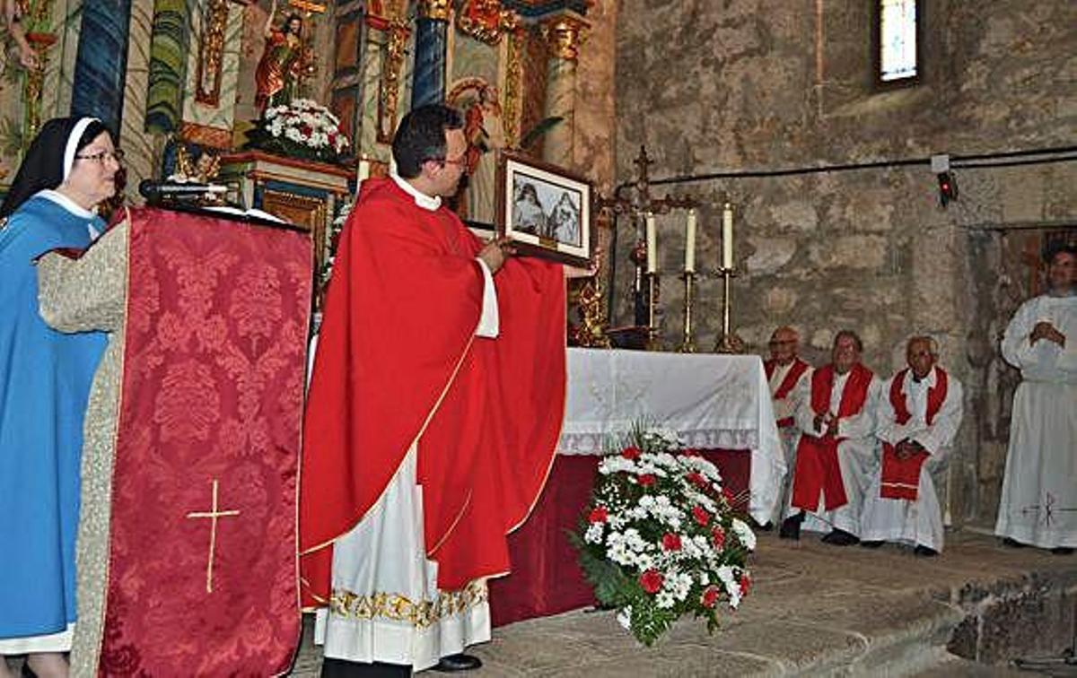 El párroco Fernando García muestra el cuadro de las mártires regalado por las Concepcionistas, junto a familiares en el centro. A la derecha, asistentes en el beso de la reliquia .
