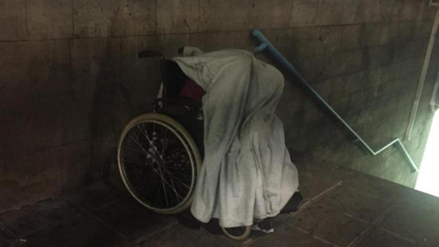 El hombre, con una sábana de un hospital tapándolo, duerme en las escaleras de la Estación de Guaguas de San Telmo.