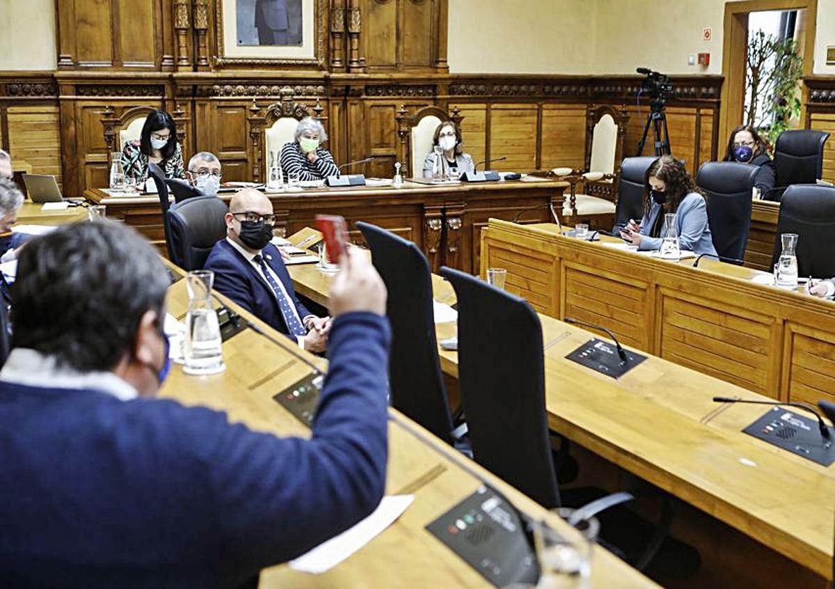 Pelayo Barcia muestra una tarjeta de la renta social a Natalia González, al fondo a la derecha. | Marcos León