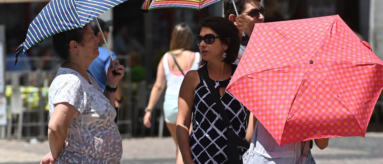 Diverses persones es protegeixen del sol amb paraigua