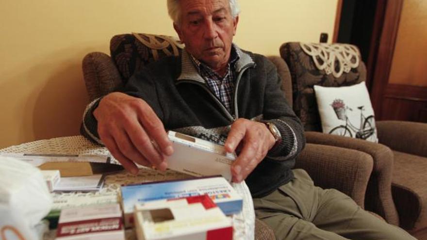 Armando Arnaldo, en el salón de su casa, muestra las medicinas que toma para sus problemas cardiacos.