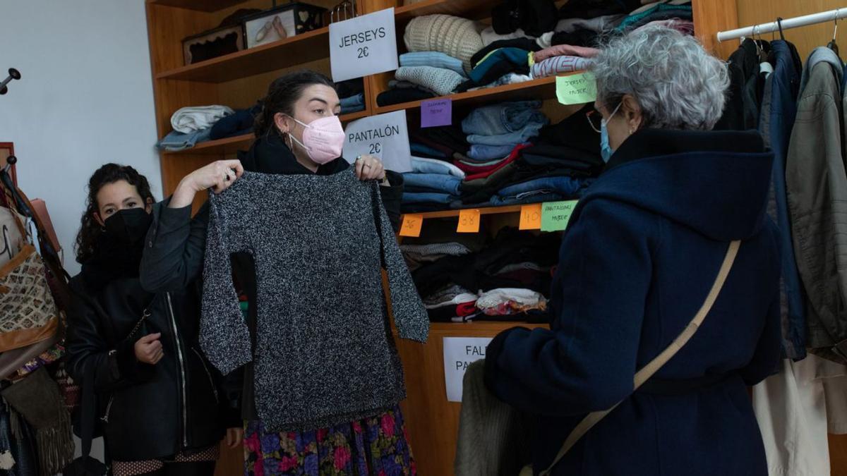 Una chica se prueba una de las prendas del mercadillo solidario de ropa de segunda mano.