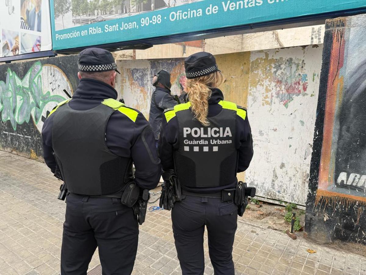 Una pareja de la Guardia Urbana de Badalona presencia como un operario sella la entrada del solar, recientemente desocupado
