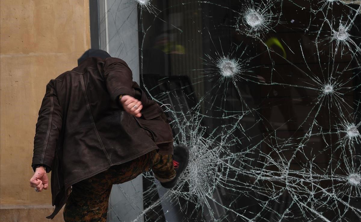 Un manifestante rompe la ventana de un banco durante el día de huelga convocada por la Confederación General de Trabajadores de Francia (CGT), en París.