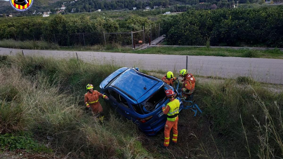 El coche siniestrado, con los bomberos que han rescatado a la mujer.