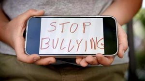 Un niño muestra en una pantalla de móvil un lema contra el bullying, en un colegio de Madrid.