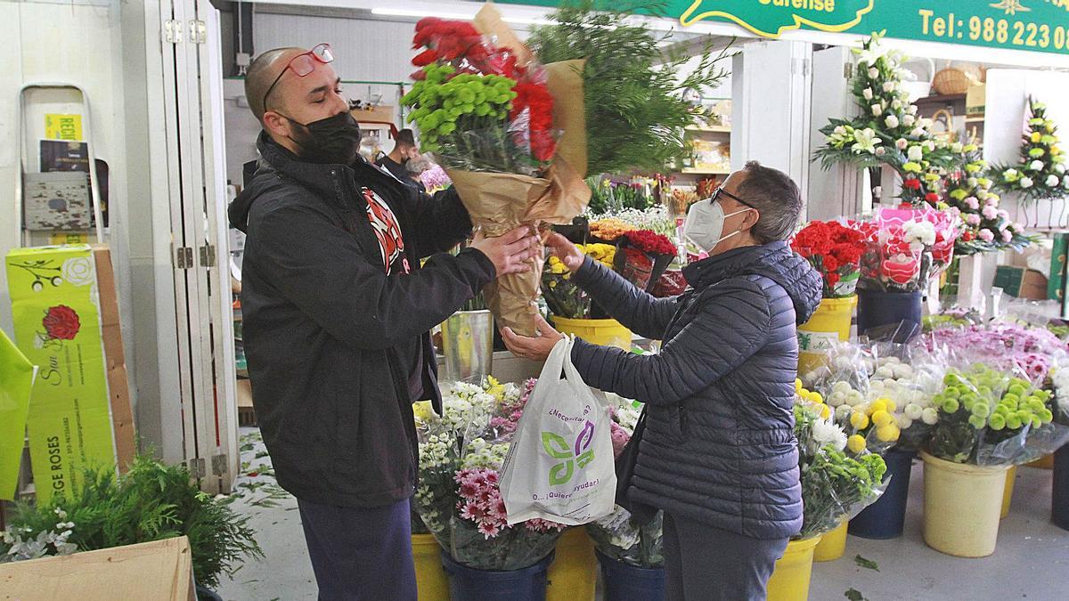 Rosa recoge varios paquetes de flores en el puesto de Milagros Albitos para montar sus propios centros en casa. |   // IÑAKI OSORIO