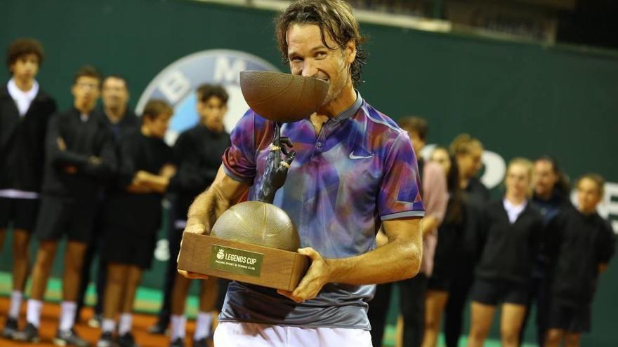 Carlos Moyá muerde el trofeo, al más puro estilo de su pupilo Rafel Nadal, de campeón de la ´Legens Cup´ en Palma.