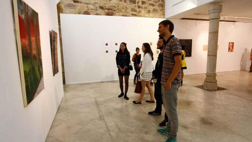 Varios de los creadores observan algunas de las piezas exhibidas en la Alhóndiga.