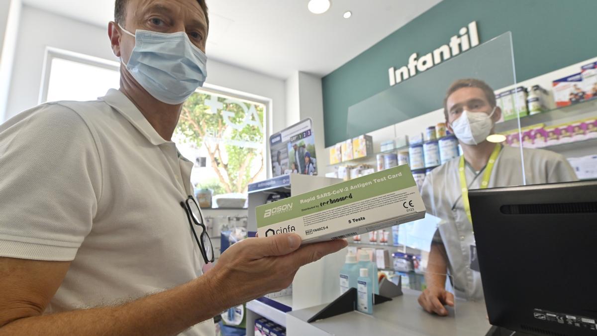 Un cliente muestra una caja de tests de antígenos en una de las farmacias de Castellón.