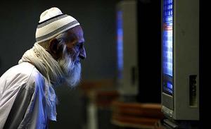 Un home observa el preu de les accions en una pantalla de televisió durant una sessió de negociació a la Borsa de Karachi (Pakistan).
