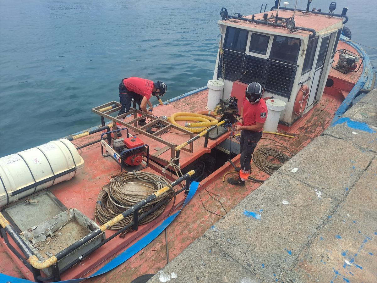 Los bomberos achican agua del barco que se hundía en Puerto Naos, en Arrecife, este viernes.