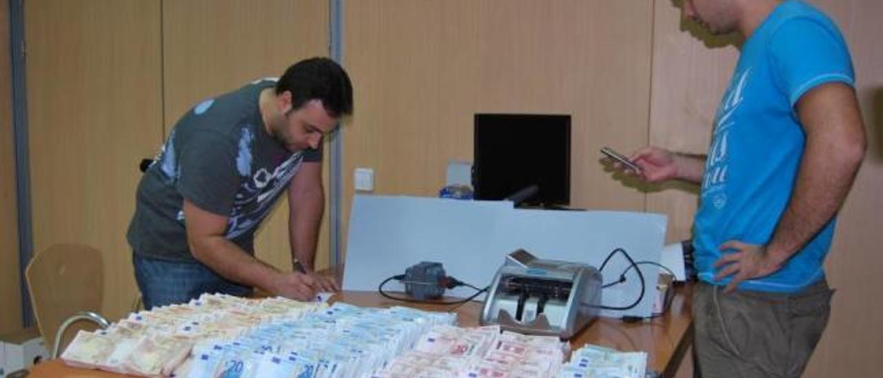 Agentes cuentan los billetes encontrados en bolsas de basura en el poblado.