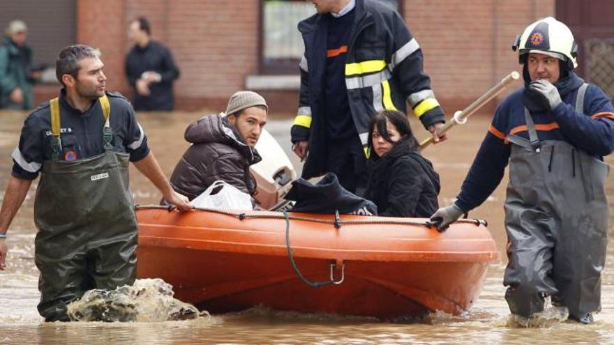 Los bomberos evacuan en un bote a una familia por una calle anegada en Tibize (Bélgica).