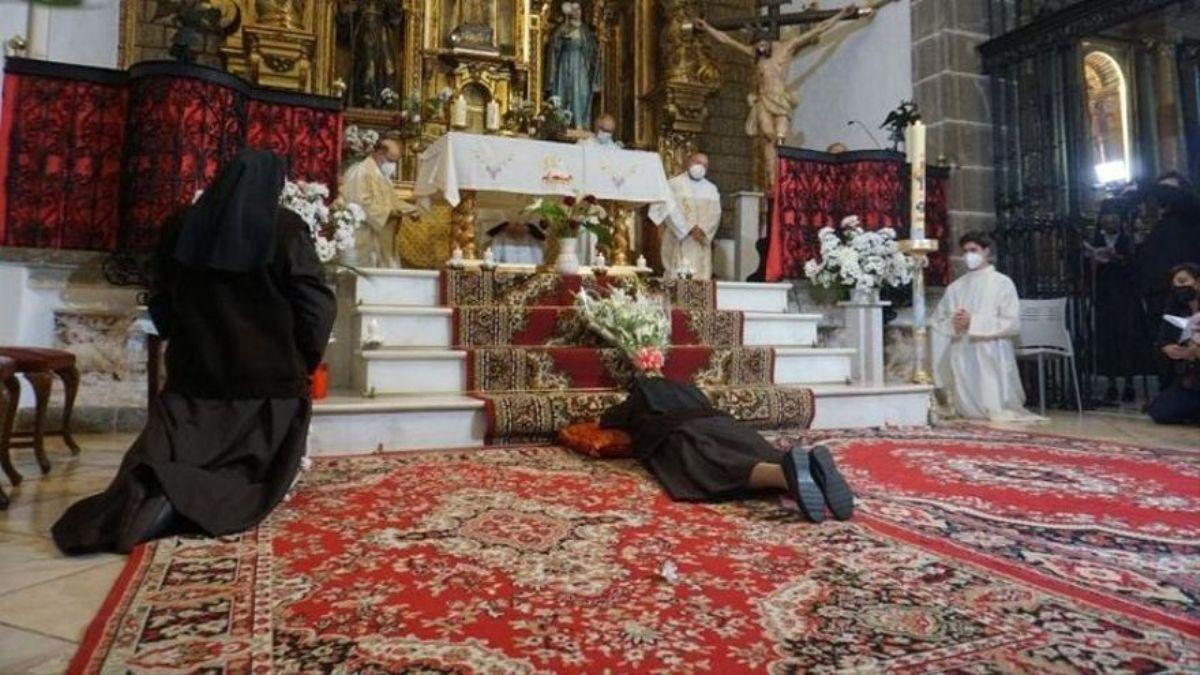 Unas monjas, arrodilladas ante un altar en donde hay tres sacerdotes