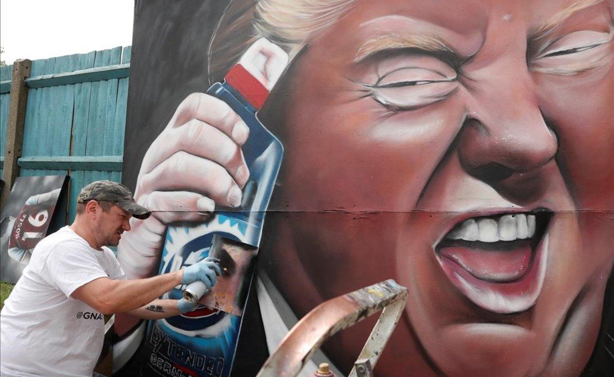 Dave Nash, de Gnasher Murals, usa espray para crear un mural en la localidad inglesa de Royston. En la obra aparece Donald Trump sosteniendo una botella del gel limpiador Domestos.