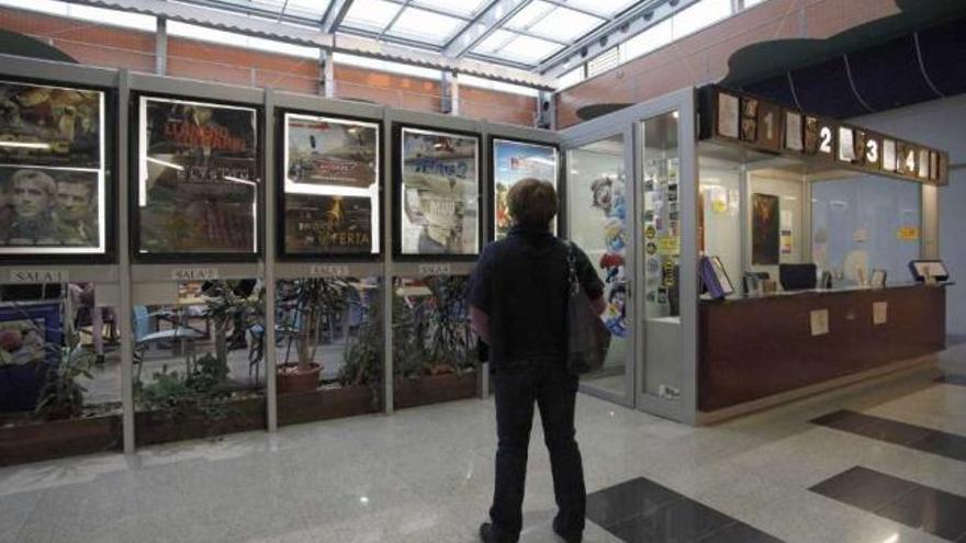 Un cliente observa la cartelera de los cines al lado de las taquilla.  // Bernabé/Gutier