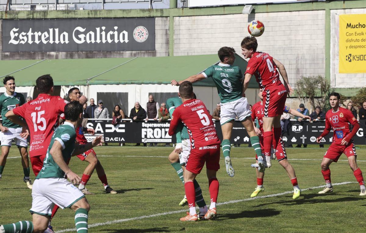 Sola, del Coruxo, salta de cabeza con Maxi, de la Sarriana, durante la segunda parte del partido de ayer. | ALBA VILLAR