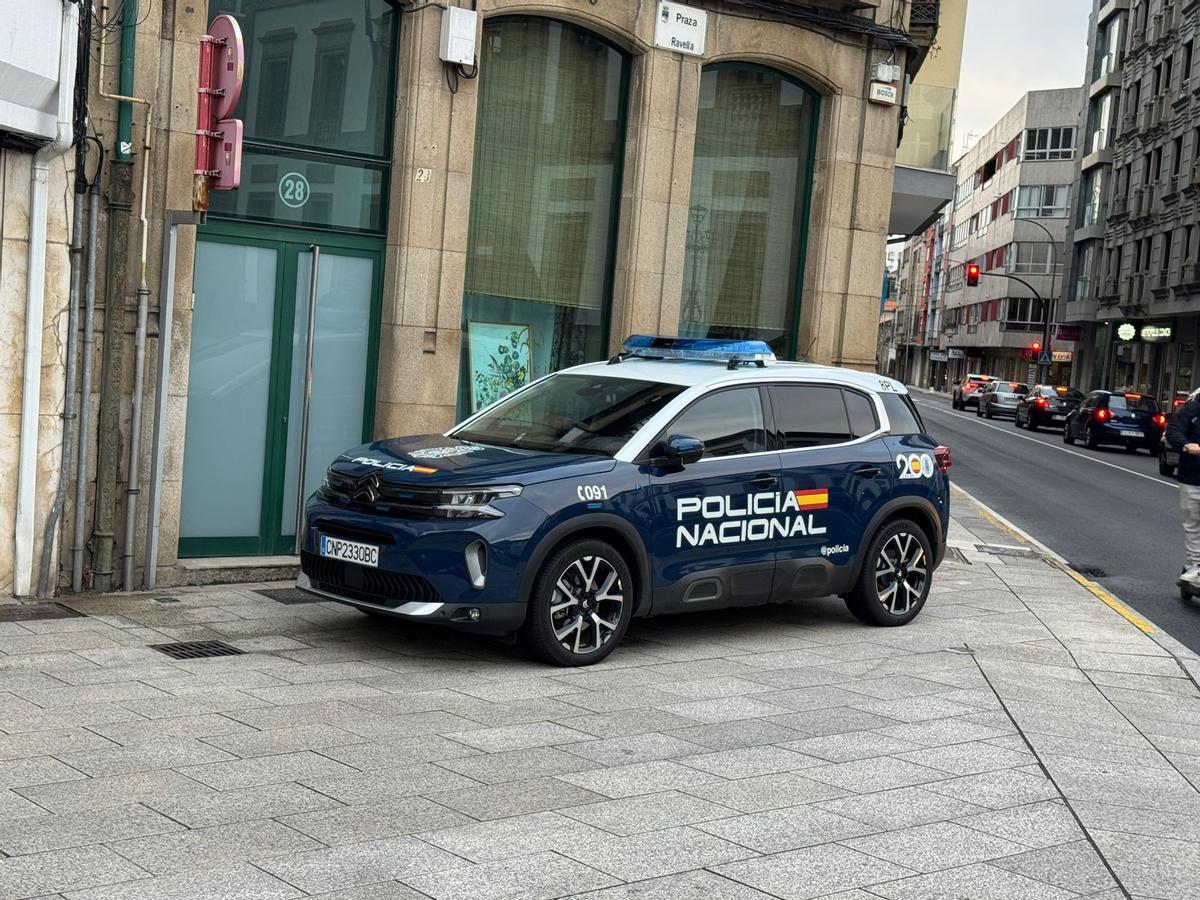 Coche policial situado en la esquina de la plaza, a una decena de metros de la entrada del edificio donde se está haciendo el registro.