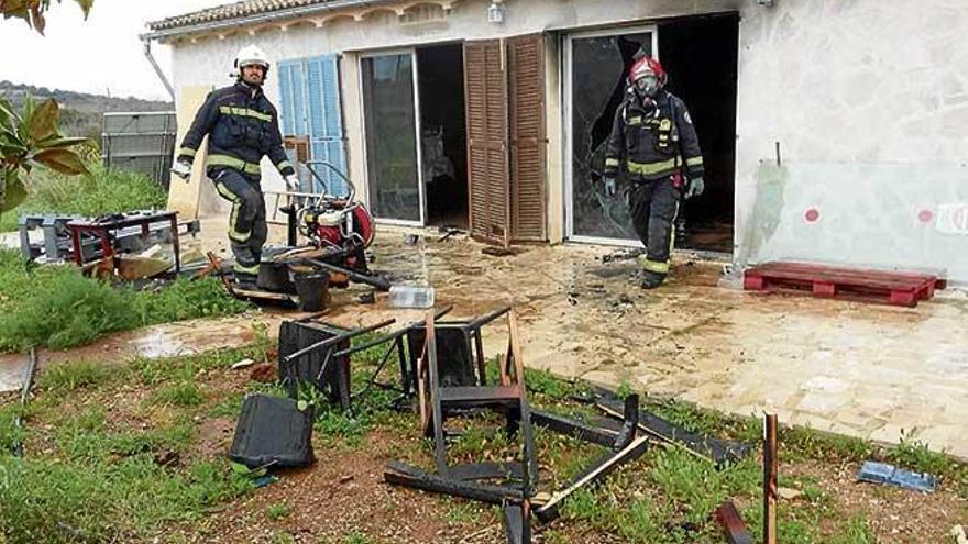 Bomberos sacan los muebles destrozados al exterior de la vivienda.