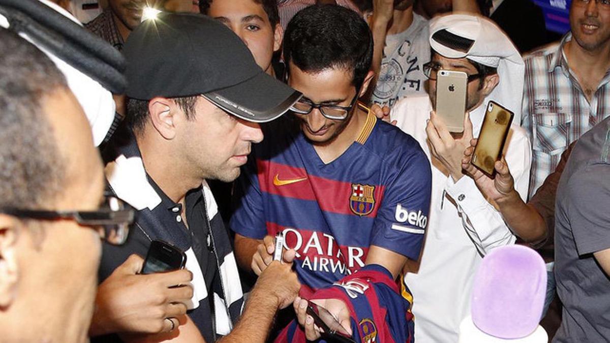 Xavi firma un autógrafo a un aficionado, a su llegada al aeropuerto de Doha